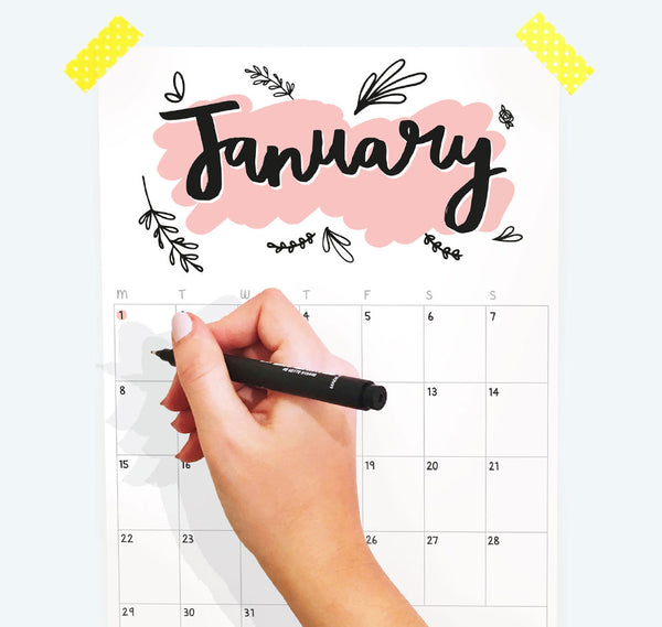 Photo of the calendar with someone about to write on it. Showing the month January.